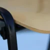 Stapelstuhl mit schwarzen Ovalrohrgestell und Sitz aus Buche-Schichtholz Detailaufnahme